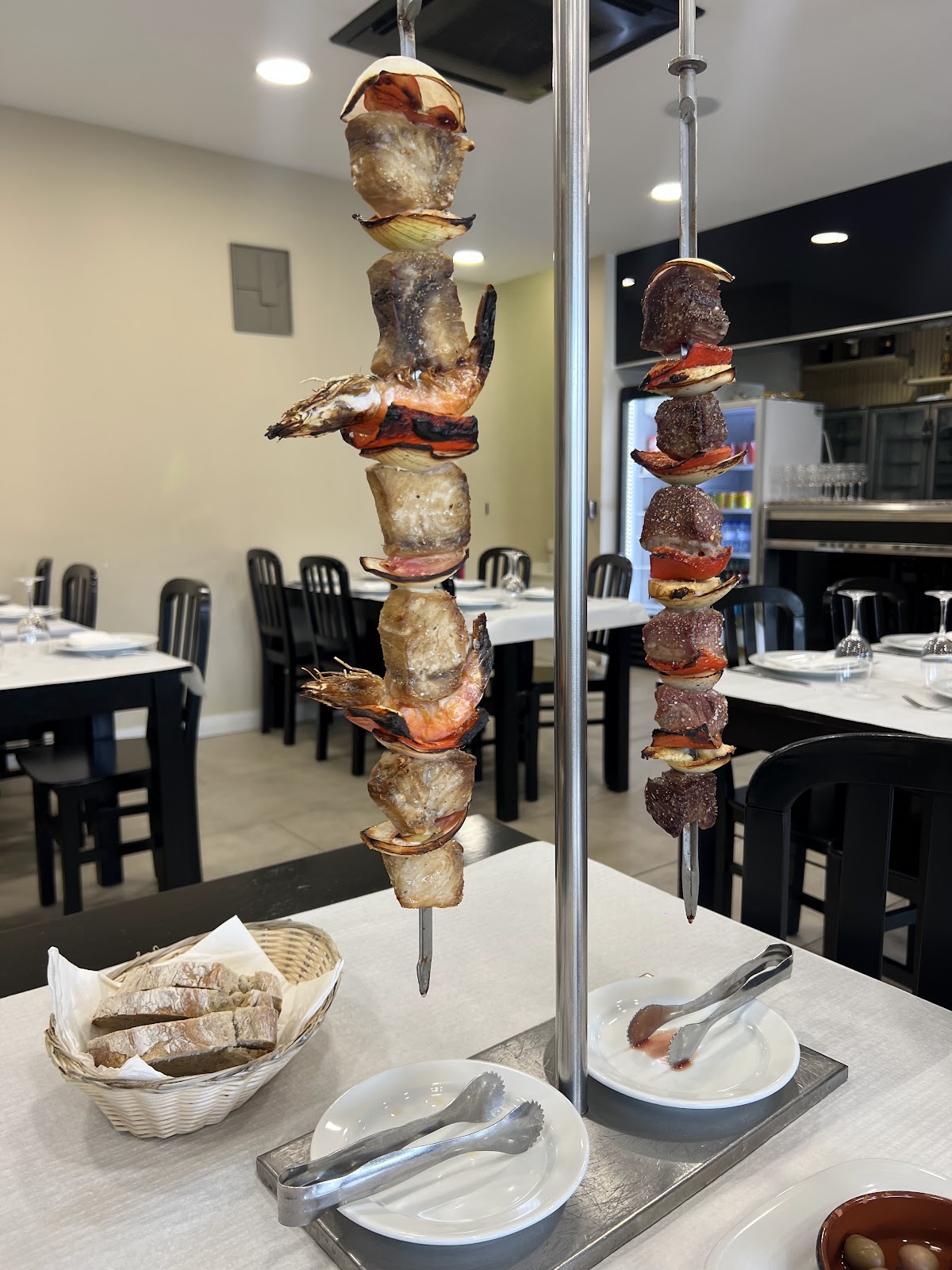 Espeto vertical de carne e camarão grelhados no carvão, plantado na mesa